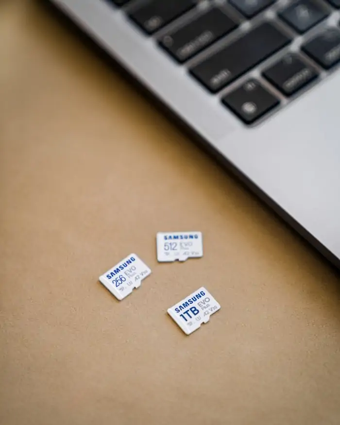 Several microSD memory cards resting on a desk beside a laptop.