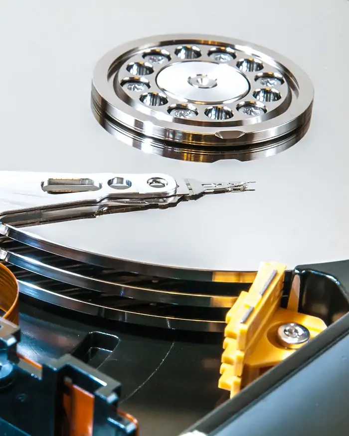 Close-up inside an opened hard disk drive, showing stacked platters and the actuator arm.