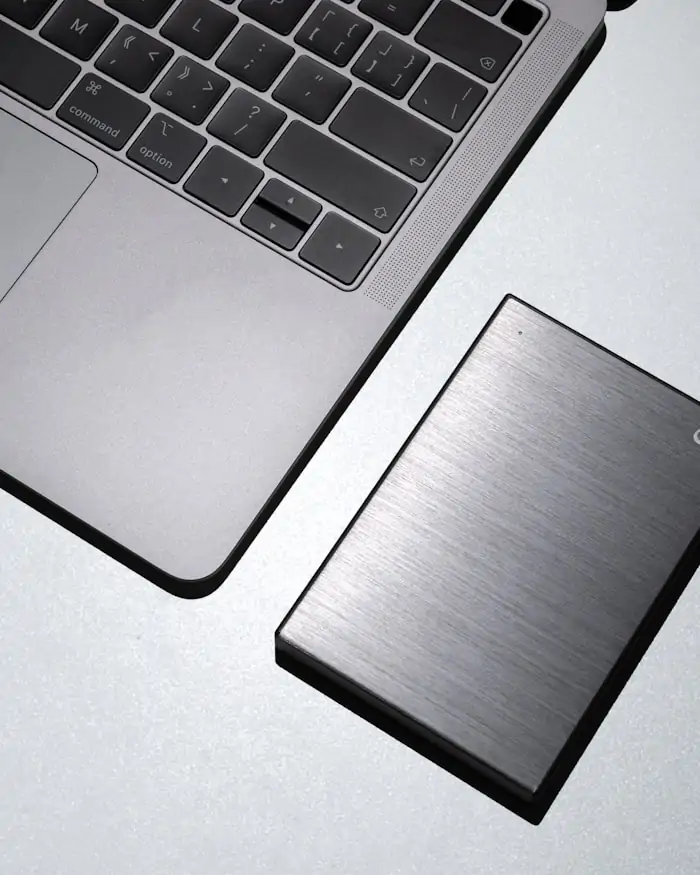 A portable external hard drive resting beside a closed laptop.